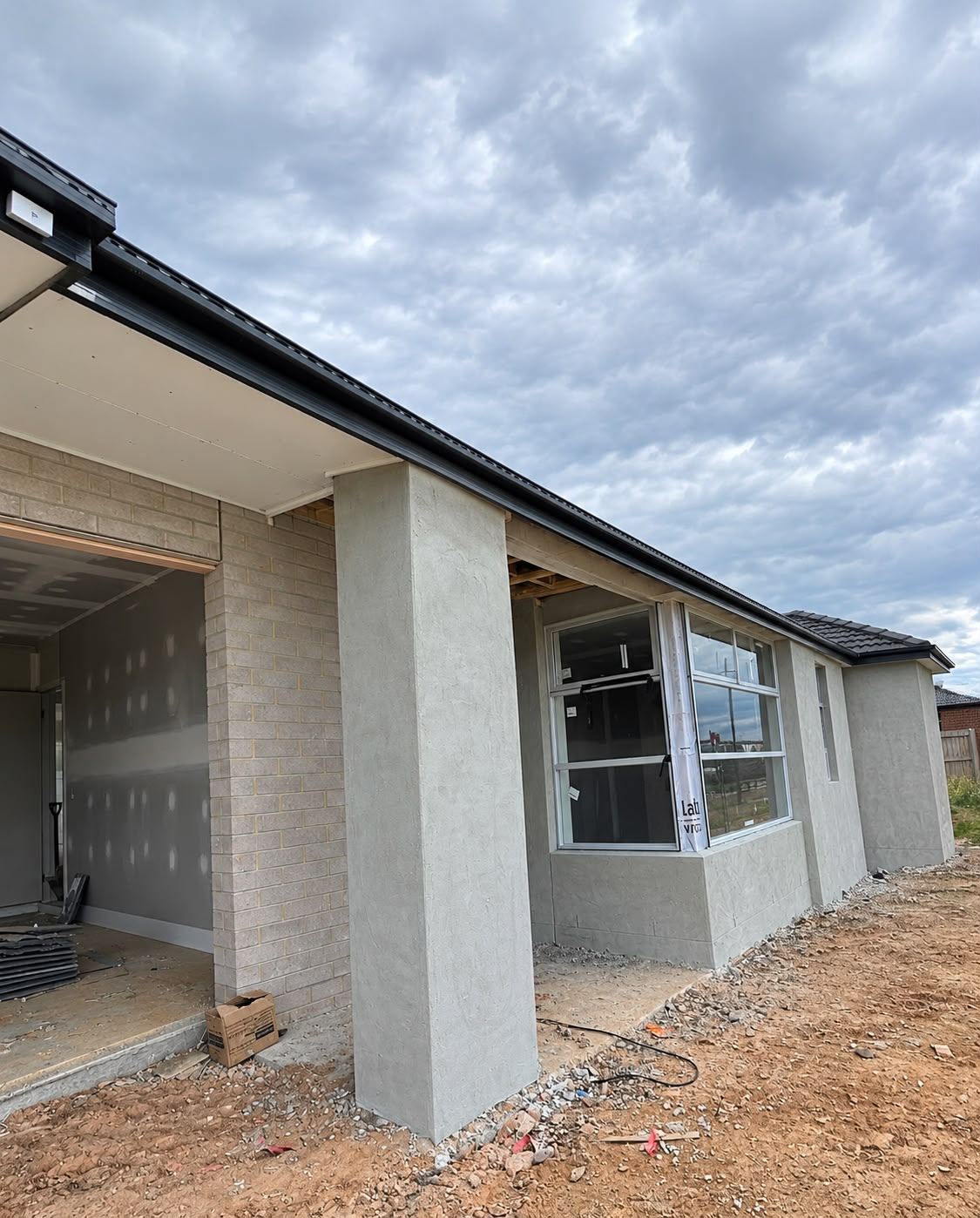 Front porch with rendered columns and installed window frames at lock-up